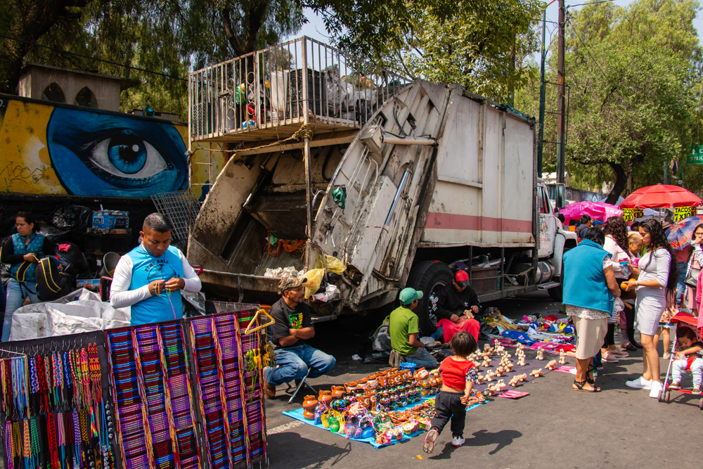 A garbage truck surrounded by street vendors